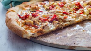 chicken and red pepper pizza on a seasoned pizza stone