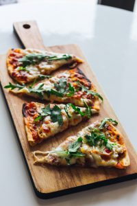 pizza slices with arugula on a wooden serving board