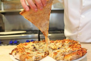Cheese pull on a cut pizza in a kitchen