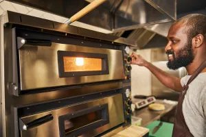 man operating pizza oven in pizzeria