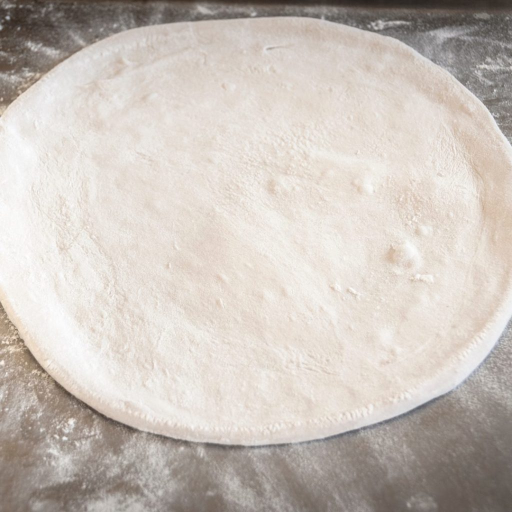 pizza dough stretched out on a wooden board