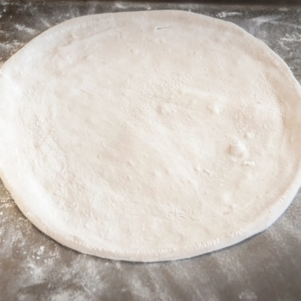 pizza dough stretched out on a wooden board