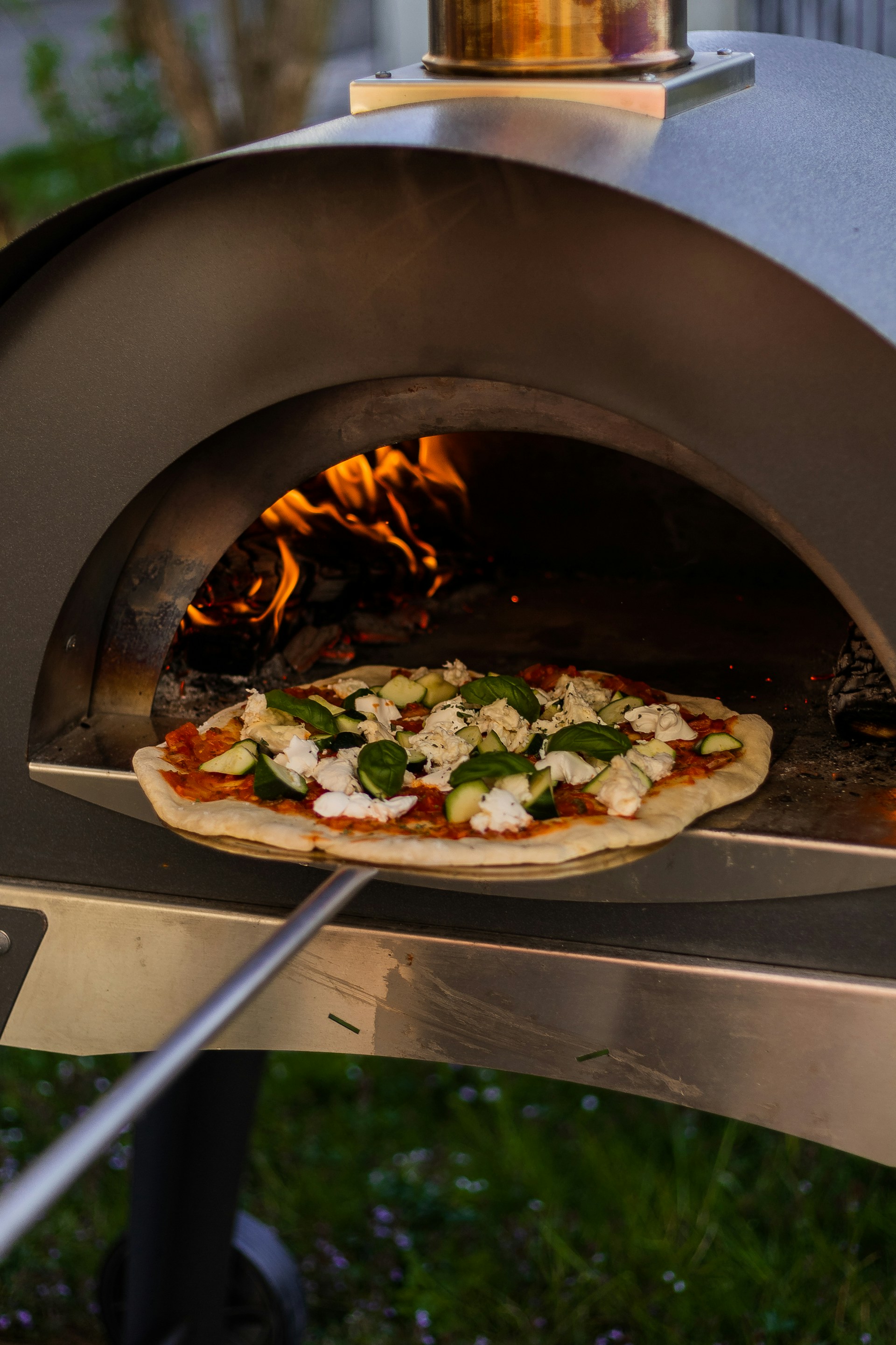 wood fired pizza oven with pizza on peel
